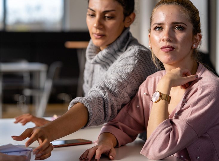 Zwei Frauen sitzen gemeinsam an einem Tisch und besprechen Unterlagen
