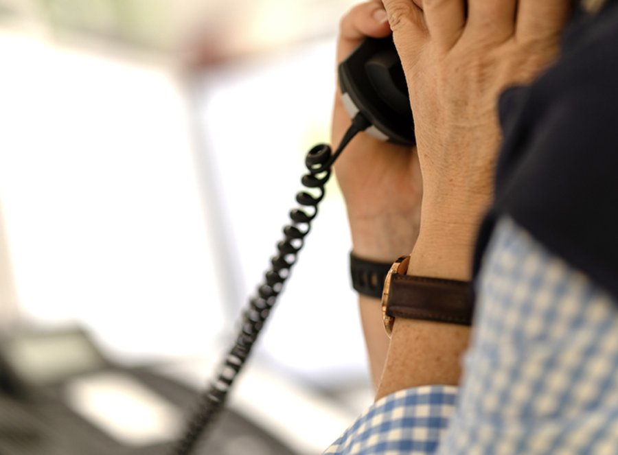 Person telefoniert mit einem Wähltelefon